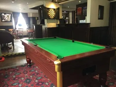 a green pool table in a room with a clock at The Bridge Inn in Tillicoultry