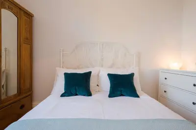 a bedroom with a white bed with two blue pillows at Historic Edinburgh 1890s Home Turned Relaxing Retreat in Edinburgh