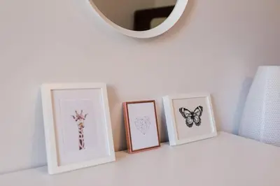a shelf with three pictures of butterflies and a mirror at Historic Edinburgh 1890s Home Turned Relaxing Retreat in Edinburgh