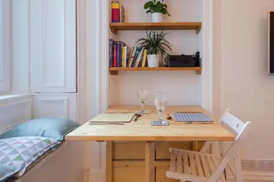 a wooden table with two laptops and glasses on it at Historic Edinburgh 1890s Home Turned Relaxing Retreat in Edinburgh