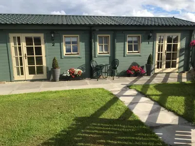 a green house with a lawn in front of it at Auchenlea lodges in Glasgow