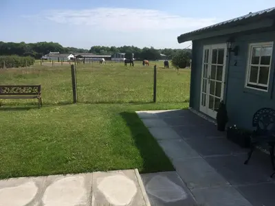 a house with a bench and a field with horses at Auchenlea lodges in Glasgow
