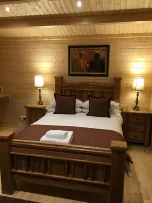 a bedroom with a large bed with two lamps at Auchenlea lodges in Glasgow