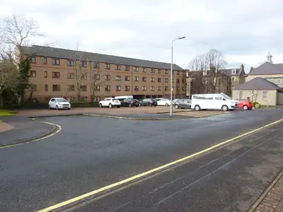 a parking lot with cars parked in front of a building at Paisley Central Apartment #2 in Paisley