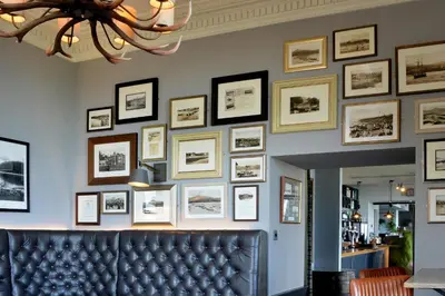 a wall with pictures on a wall with a couch at The Douglas Hotel in Brodick