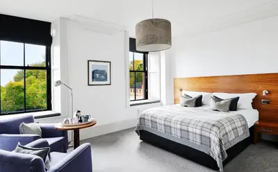 a bedroom with a bed and two chairs at The Douglas Hotel in Brodick