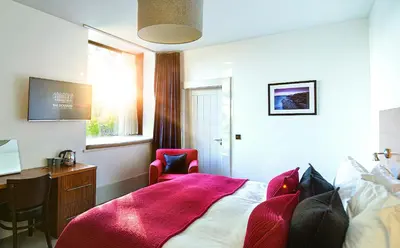 a bedroom with a bed and a desk and a window at The Douglas Hotel in Brodick