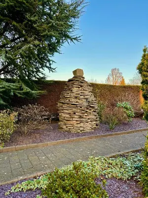 a stone chimney in the middle of a garden at The Cairn Residence in Edinburgh