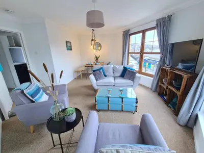 a living room with blue couches and a table at The Clamshell, Oban in Oban