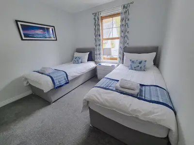 a bedroom with two beds and a window at The Clamshell, Oban in Oban