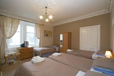 a bedroom with three beds and a television in it at Arbour Guest House in Oban