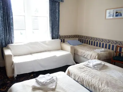 a room with three beds and a couch and a window at Arbour Guest House in Oban