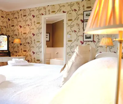 a bedroom with a large white bed with floral wallpaper at The Creggans Inn in Strachur