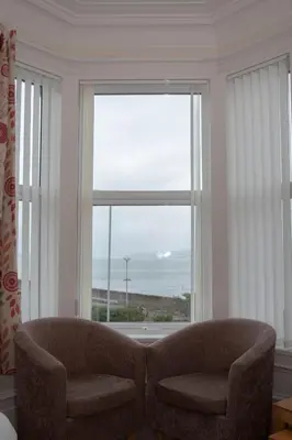 a living room with a chair and a large window at Craignelder Hotel in Stranraer