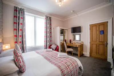 a bedroom with a bed and a desk and a window at Craignelder Hotel in Stranraer