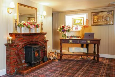a living room with a brick fireplace and a mirror at The Lagg in Lagg