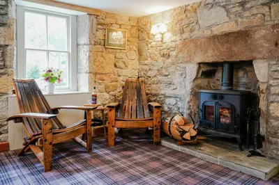 a living room with a wood stove and two chairs at The Lagg in Lagg