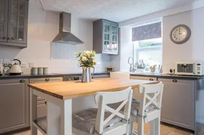a kitchen with a wooden table and two white chairs at Country Nest in Carnwath