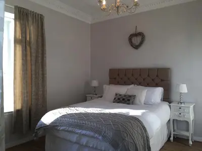 a bedroom with a large bed and a chandelier at Country Nest in Carnwath