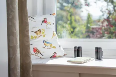 a pillow with birds on it sitting on a window sill at Country Nest in Carnwath