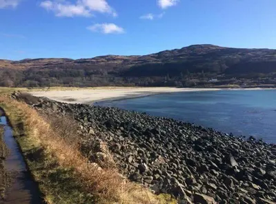 a large group of rocks on the shore of a body of water at The Old School in Salen