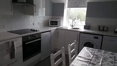 a white kitchen with a stove and a microwave at The Old School in Salen
