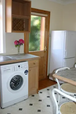 a kitchen with a washing machine and a refrigerator at Garden Cottage in Prestwick