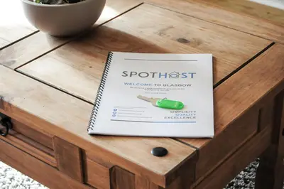 a book on a coffee table with a pen on it at A Spacious Flat with Character - Private Car Space in Paisley