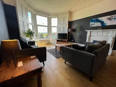 a living room with two couches and a fireplace at A Spacious Flat with Character - Private Car Space in Paisley