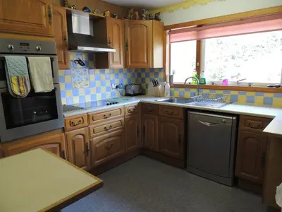 a kitchen with wooden cabinets and a sink and a window at Atlantic Bay Cottage in Clachan