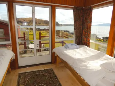 a bedroom with a bed and a large window at Atlantic Bay Cottage in Clachan