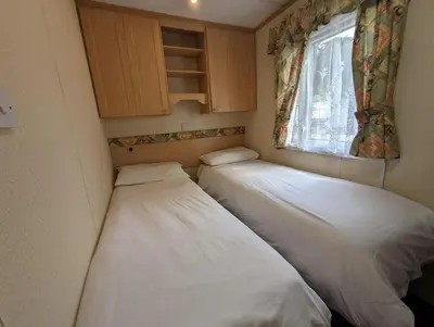two beds in a small room with a window at The Senator 69 in Dunoon