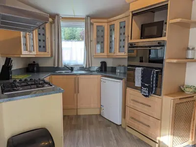 a kitchen with wooden cabinets and a stove top oven at The Senator 69 in Dunoon