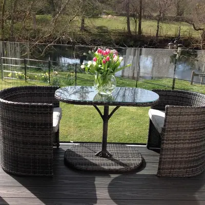 a glass table with a vase of flowers on a deck at Riverbank in Callander
