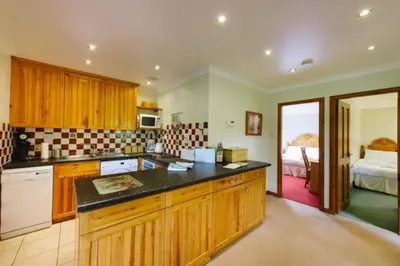 a kitchen with wooden cabinets and black counter tops at The Buzzard Lodge 2 bedroom sleeps up to 4 in Crianlarich