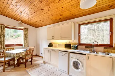 a kitchen with a washer and dryer and a table at Fisher Lodge sleeps up to 2 in Crianlarich