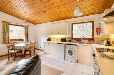 a kitchen and dining room with a washer and dryer at Fisher Lodge sleeps up to 2 in Crianlarich