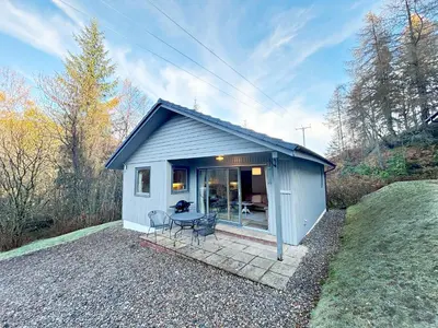 a small blue shed with a table and chairs at Fisher Lodge sleeps up to 2 in Crianlarich