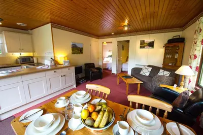 a kitchen and a living room with a table with fruit on it at Heron Lodge sleeps up to 4 with free wifi in Crianlarich