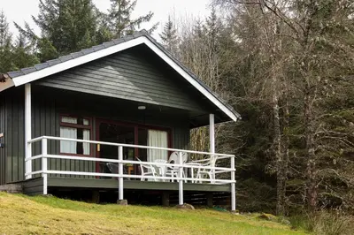 a small house with a porch and a deck at Heron Lodge sleeps up to 4 with free wifi in Crianlarich
