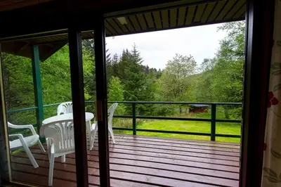 a screened in porch with a table and chairs on it at Heron Lodge sleeps up to 4 with free wifi in Crianlarich