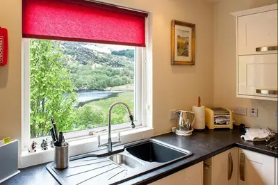 a kitchen with a sink and a window at Kingfisher Lodge with sensational loch views in Crianlarich