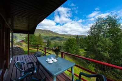 a wooden deck with a table and chairs on it at 2 bedroom lodge with stunning loch mountain views in Crianlarich