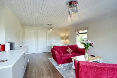 a living room with a red couch and a table at 2 bedroom lodge with stunning loch mountain views in Crianlarich