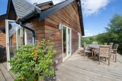 a wooden deck with a table and chairs on a house at Mains of Taymouth Country Estate 5* Houses in Kenmore
