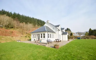 a large white building with a grassy field in front at Feochan Bheag in Oban