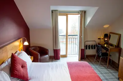 a hotel room with a bed and a balcony at The Inn on Loch Lomond in Luss