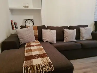 a brown couch with pillows in a living room at Rozina Apartment in Paisley