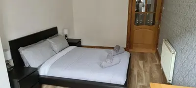 a bedroom with a bed with shoes on it at Rozina Apartment in Paisley