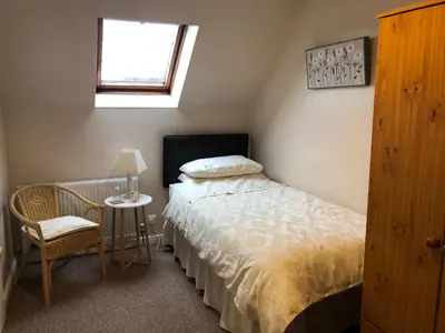 a bedroom with a bed and a table and a window at Fairview Bed and Breakfast in Airdrie